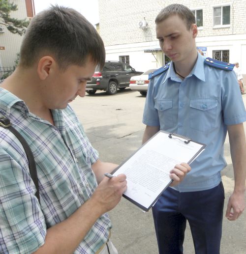 Неизвестный работник прокуратуры вручает председателю правления региональной правозащитной организации «Стоп, коррупция!» Максиму Семенову «текст» без названия.