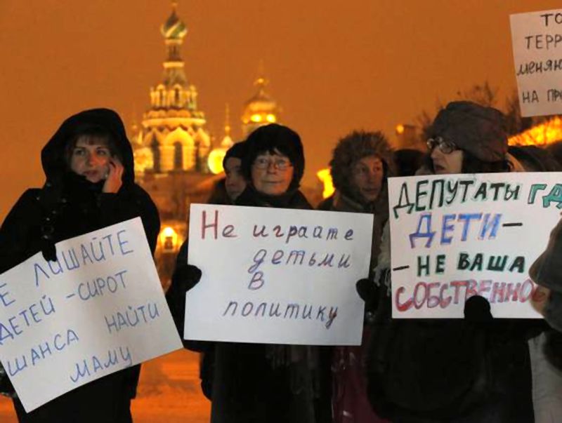 Opposition activists hold posters reading «Do not involve children in politics» and «Lawmakers, children are not your ownership» during a protest against a bill banning U.S. adoptions of Russian children in St. Petersburg, Russia, on, Dec. 26. (Photo: Dmitry Lovetsky, AP)/Активисты оппозиции держат плакаты: «Не вовлекать детей в политику» и «Законодатели, дети не ваша собственность» во время акции протеста против законопроекта о запрете США усыновления русских детей. Санкт-Петербург, Россия, 26 декабря. (Фото: Дмитрий Ловецкий, AP)