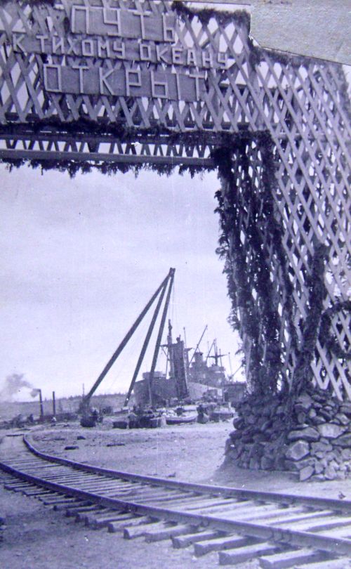«Путь к Тихому океану открыт» изображена триумфальная арка, украшенная гирляндами цветов и флагами; за аркой хорошо просматривается морской причал и залив. Другими словами, текстовые документы и фотоматериал однозначно говорят, что поезд, открывший сквозное движение на линии Пивань - Ванино прибыл к морскому берегу.