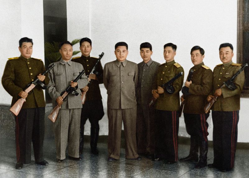 Ким Ир Сен вручает кадровым работникам автоматы, произведенные впервые в Корее, и фотографируется с ними на память. Октябрь 38 г. чучхе (1949).