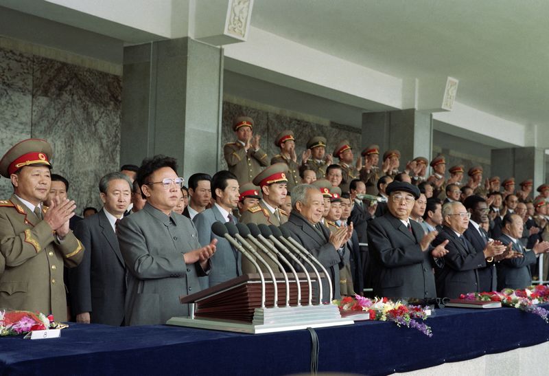 Ким Ир Сен и Ким Чен Ир на трибуне военного парада в честь 60-летия основания Корейской Народно-революционной армии. Апрель 81 г. чучхе (1992).