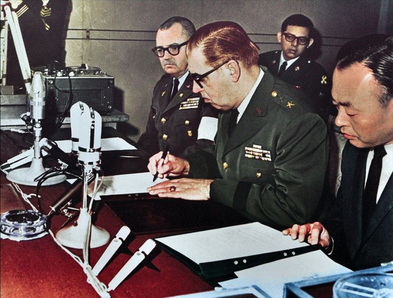 Генерал-майор сухопутных войск США Гилберт Вудворд 
от имени правительства США подписывает извинительный акт.