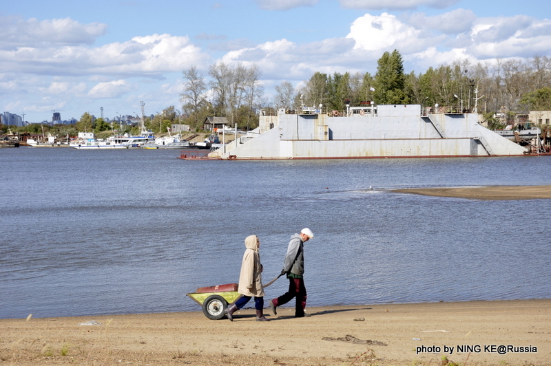 Двое пожилых людей идут через остров, позади - док./ 两名老人走过岛上少数的企业——船坞